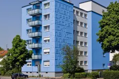 Außenaufnahme eines Mehrfamilienhauses mit blauer Fassade, gestaltet mit StoDeco Buchstaben aus Verolith®