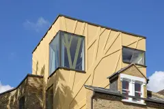Detailaufnahme einer kubisartigen, gelben Fassade, gestaltet mit plastischen StoDeco Fassadenelementen in Baum-Ast-Struktur